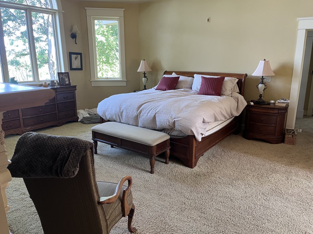 Before: primary bedroom with a dark wood sleigh bed and dated furniture